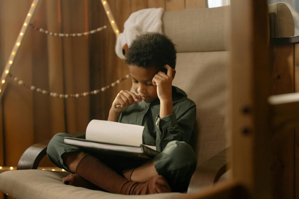 A young child intensely focused on drawing while sitting indoors in a cozy and warm setting.